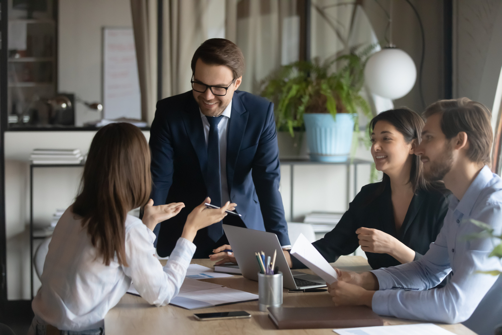 Team collaborating in an office setting with a manager leading the discussion, highlighting project management services.