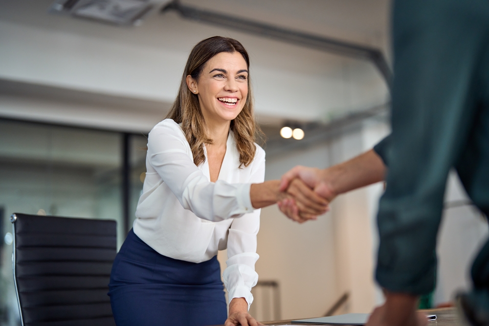 Smiling businesswoman shaking hands with a colleague, highlighting the importance of business planning services.