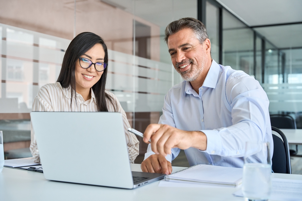 Two professionals reviewing data and strategies on a laptop during a corporate consulting session.
