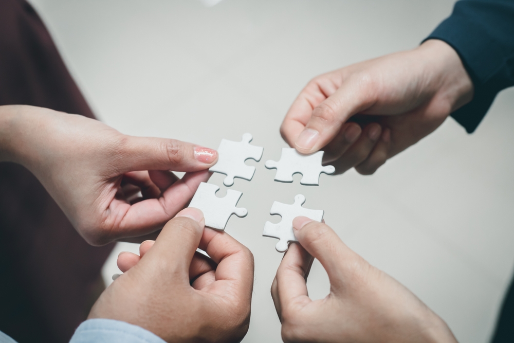 Diverse business individuals joining puzzle pieces, illustrating the importance of sustainability in modern business practices.