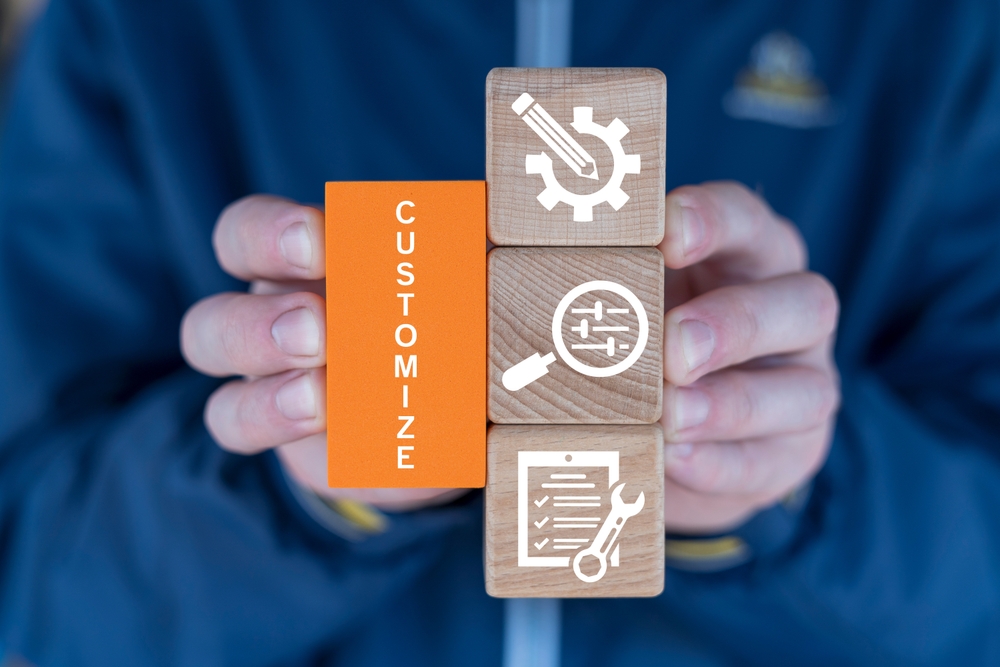 A man holds wooden blocks spelling "customize," symbolizing tailored solutions for unique business needs.