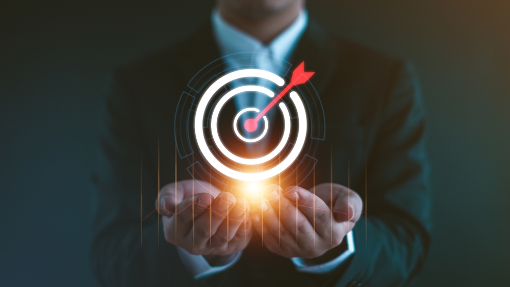 Businessman holding glowing target icon symbolizes goal alignment through effective organizational change management strategies.