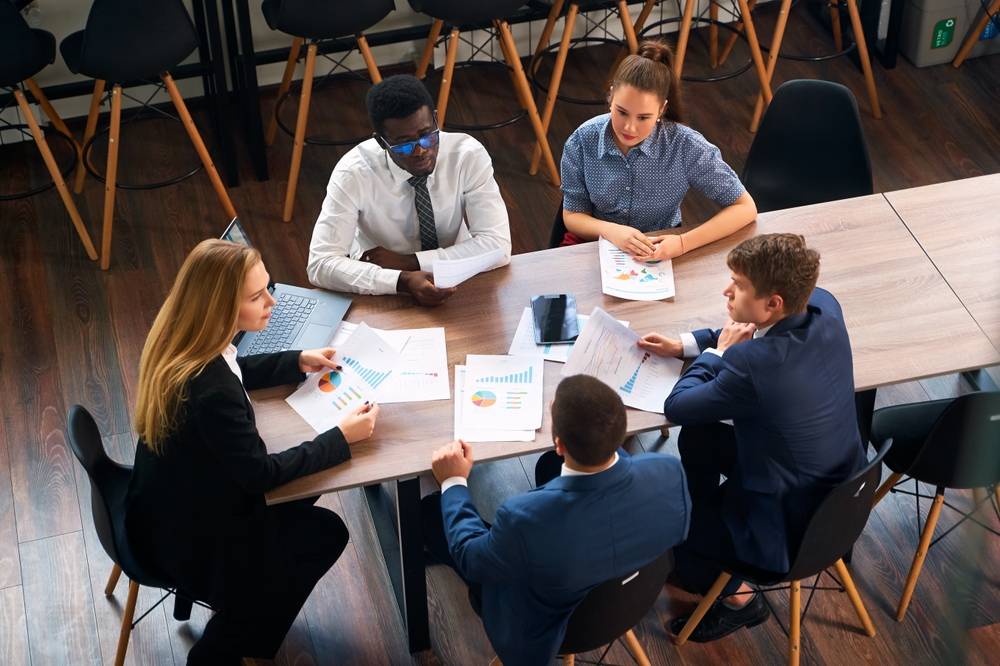 Business team seated at a table, collaborating on strategies informed by analytics and AI for effective decision-making.