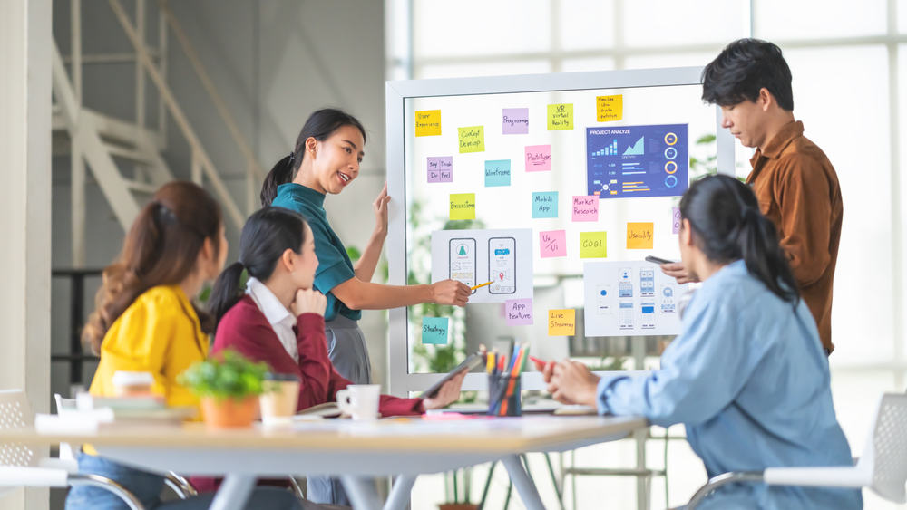 Asian business professionals collaborate in a meeting room, discussing strategies for business plan development and growth.