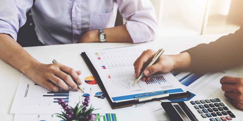 two people sitting at a desk analyzing different graphs and pie charts