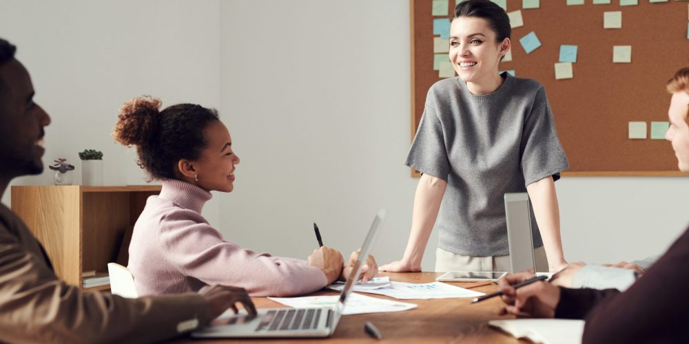 Lady standing at the table smiling at her co workers